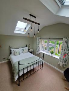 a bedroom with a bed and two windows at Idyllic period cottage, Ramsbury, Nr Marlborough in Ramsbury