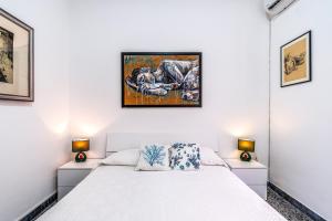 a white bedroom with a bed and two lamps at Al Portico in Avola