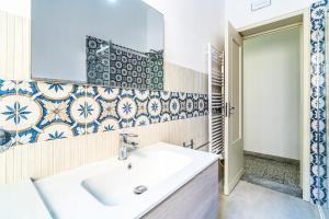 a bathroom with a white sink and blue and white tiles at Al Portico in Avola +13 photos