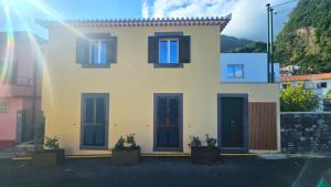 a white house with blue shutters and a mountain at Casa Amarela do Redondo in Seixal