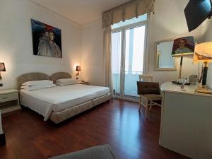 a bedroom with a bed and a desk and a window at B&B Palazzo Sant'Alfano in Catania