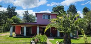 a pink house with a palm tree in front of it at Cabañas Donkaia in La Población