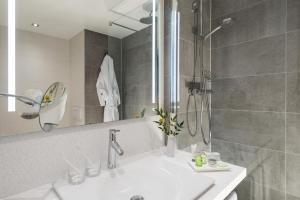 a white bathroom with a shower and a sink at NH Hamburg Altona in Hamburg