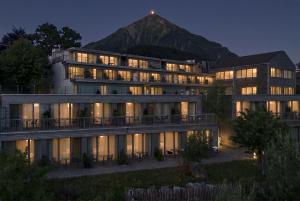 a large building with a mountain in the background at Hotel Seaside in Spiez
