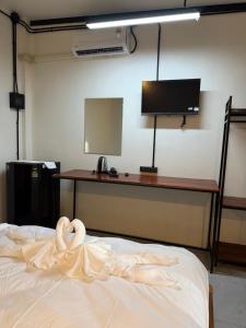 a bedroom with a bed with a desk and a television at Mountainblues Hotel in Pai