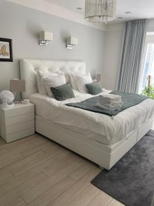 a white bedroom with a large white bed with pillows at Le Reflet du Lac in Annecy