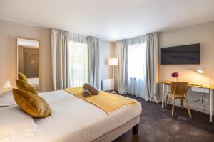 a hotel room with a bed and a desk and a table at Hôtel Antares & Spa in Honfleur +27 photos