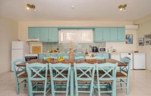 a kitchen with blue cabinets and a table and chairs at Sunrise Stone Villa in Agios Nikolaos