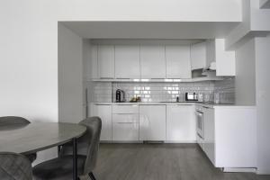 a kitchen with white cabinets and a table with chairs at Magic Kloverhuset Harbour Hotel, a member of Radisson Individuals in Bergen +175 photos