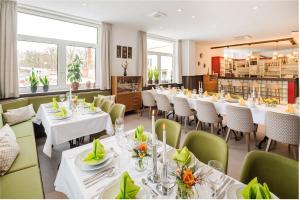 a restaurant with white tables and green chairs at Lübsche Thorweide in Wismar +10 photos
