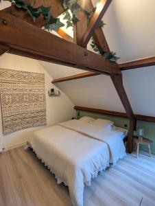 a bedroom with a white bed in a attic at Le Moment Normand in Émalleville