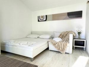 a white bedroom with a bed and a chair at Green Garden Gajac in Gajac