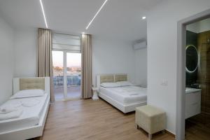 a white room with two beds and a window at SulMare Rooms in Sarandë
