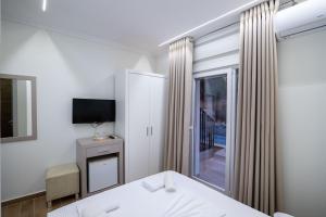 a bedroom with a bed and a tv and a window at SulMare Rooms in Sarandë