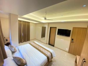 a hotel room with a bed and a flat screen tv at Hotel Banyan Crest in Solapur
