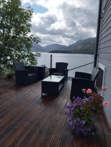 a wooden deck with chairs and a table and flowers at Sveciu namai in Vikedal +11 photos
