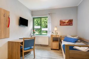 a small room with a bed and a desk and a table at Pension Pusteblume in Meyenburg