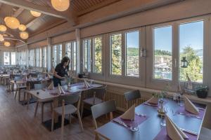 a woman standing in a dining room with tables and windows at Hotel Seaside in Spiez