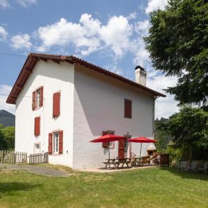 a white house with red umbrellas in front of it at Gîte Zelai Begi in Aldudes
