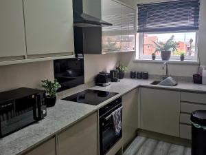 a kitchen with white cabinets and a stove top oven at Miners Lamp Apartment in Easington