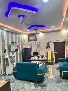 a living room with blue couches and a tv at SM Guest House in Lucknow