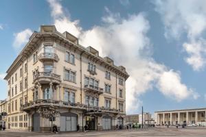 a large white building with balconies on a street at BYPILLOW Grand Central in Padova