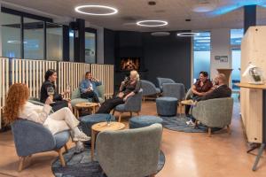 a group of people sitting in chairs in a room at Hotel Seaside in Spiez