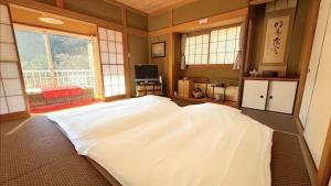a large white bed in a room with windows at 熱海の貸切温泉宿 kintsugi プライベートサウナ BBQ in Atami
