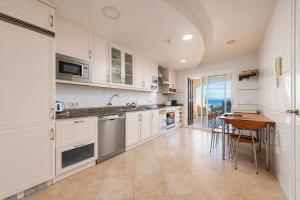 a kitchen with white cabinets and a wooden table at Villa Casa Faro in Alcanada