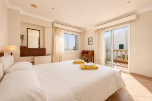 a white bedroom with a large white bed and a window at Villa Casa Faro in Alcanada +17 photos