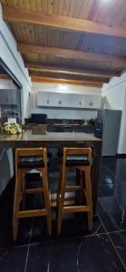 a kitchen with two wooden stools at a counter at Cabaña El Dorado, Alojamiento in Puerto Cantera