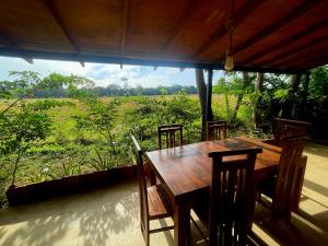 a wooden table with chairs and a view of a field at Ama Villa - Habarana in Habarana