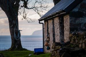 a house with a tree next to the ocean at The Croft Collective in Oban