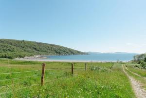 a fence in a field next to a body of water at The Croft Collective in Oban +5 photos