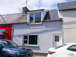 a white house with cars parked in front of it at Cottage on the Lane Dingle in Dingle