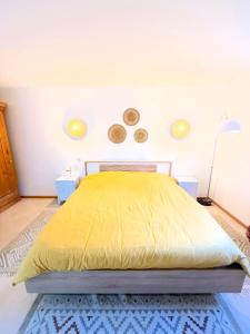 a bedroom with a yellow bed with two clocks on the wall at Le Refuge du Saule in Saint-Aubin-de-Locquenay