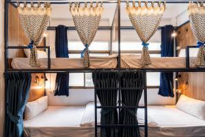 a room with two bunk beds with curtains at Arawana Hostel Silom in Bangkok
