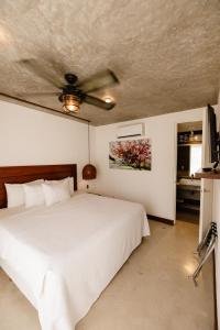 a bedroom with a white bed and a ceiling fan at Hotel Zendero Tulum in Tulum +39 photos