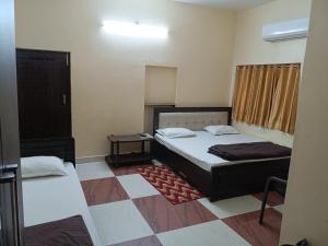 a bedroom with two beds in a room with a checkered floor at SM Guest House in Lucknow