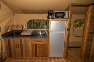 a kitchen with a sink and a refrigerator in a tent at Camping Hôtel Maui in Tournon-sur-Rhône