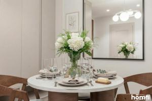 a white dining room table with a vase of flowers at Libra Luxury AC - homfi Collection in Krakow