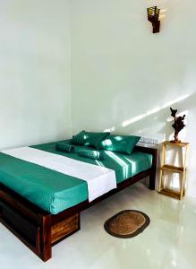 a bedroom with a bed with green and white sheets at Footmark Surf Stay in Pottuvil +17 photos