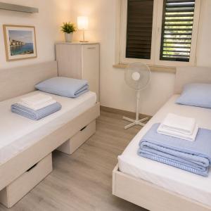 two beds in a small room with a fan at Inter-nautika doo in Jezera