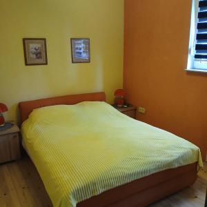 a bedroom with a bed with a yellow comforter at Soba za vise osoba in Ilijaš