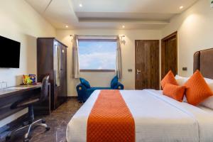 ein Hotelzimmer mit Bett, Schreibtisch und Fenster in der Unterkunft Hotel BNB Stays Near Golf Course Road in Gurgaon