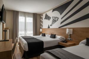 ein Hotelzimmer mit zwei Betten und einem Fernseher in der Unterkunft Estival Sporting in Pas de la Casa + 14 Fotos