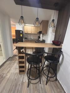 a kitchen with a table and four bar stools at Apartamento amoblado Chinchiná in Chinchiná +9 photos