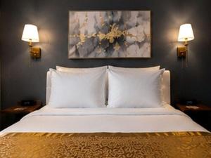ein Schlafzimmer mit einem Bett mit weißen Kissen und zwei Lampen in der Unterkunft SOVEL Hotel in Miami