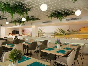a restaurant with tables and chairs and plants on the ceilings at BQ Paguera Boutique Hotel - Adults Only in Paguera