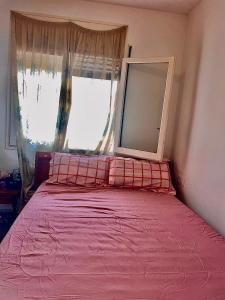 a bedroom with a pink bed with a large window at Appartement in Girona